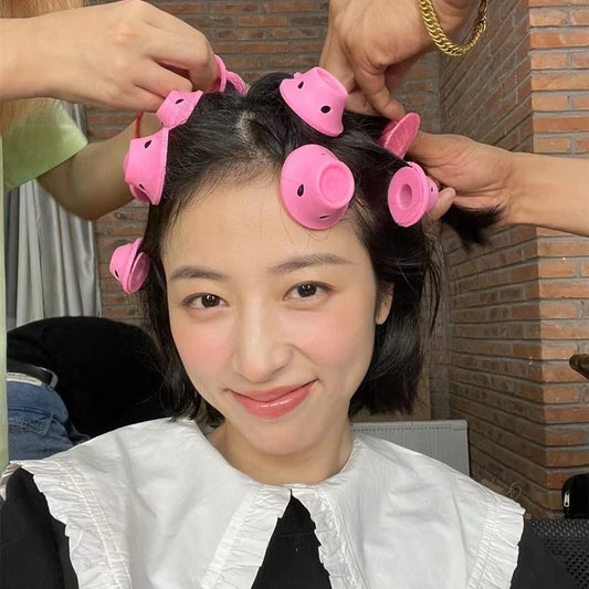 Person with pink hair rollers in their hair, smiling at the camera.